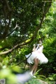 A woman in a white dress standing in the woods.